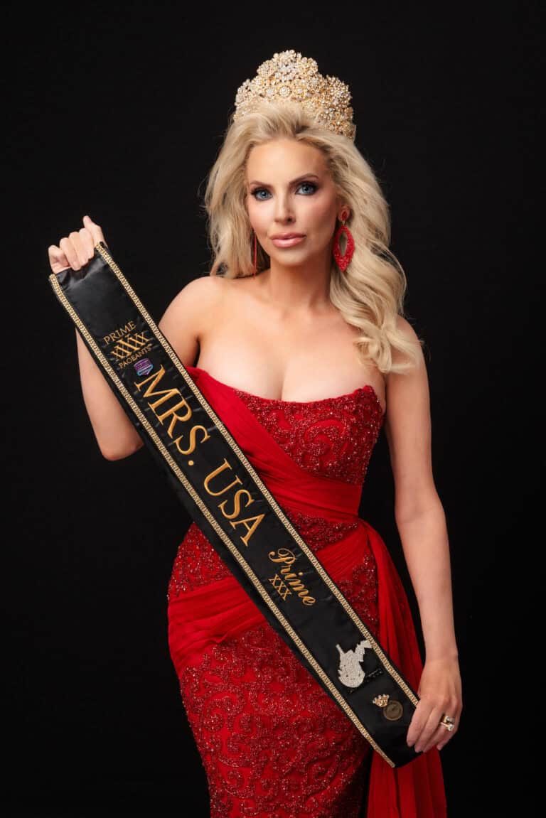 A woman in a red, jeweled gown and ornate crown holds a black sash that reads Mrs. USA, celebrating her journey from No Phone to Troomi. She has long blonde hair, red earrings, and stands against a dramatic black background.