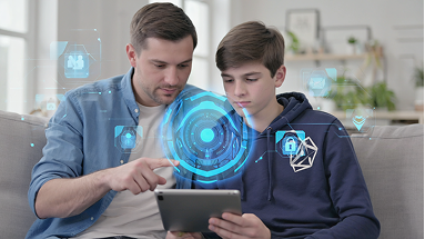 A man and a boy sit on a couch using a tablet together, with blue digital security interface graphics superimposed, suggesting a focus on cybersecurity or safe technology use.