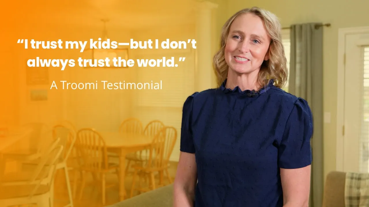 A woman in a navy dress smiles in a bright dining room. Text beside her reads: I trust my kids—but I don’t always trust the world. A Troomi Testimonial.