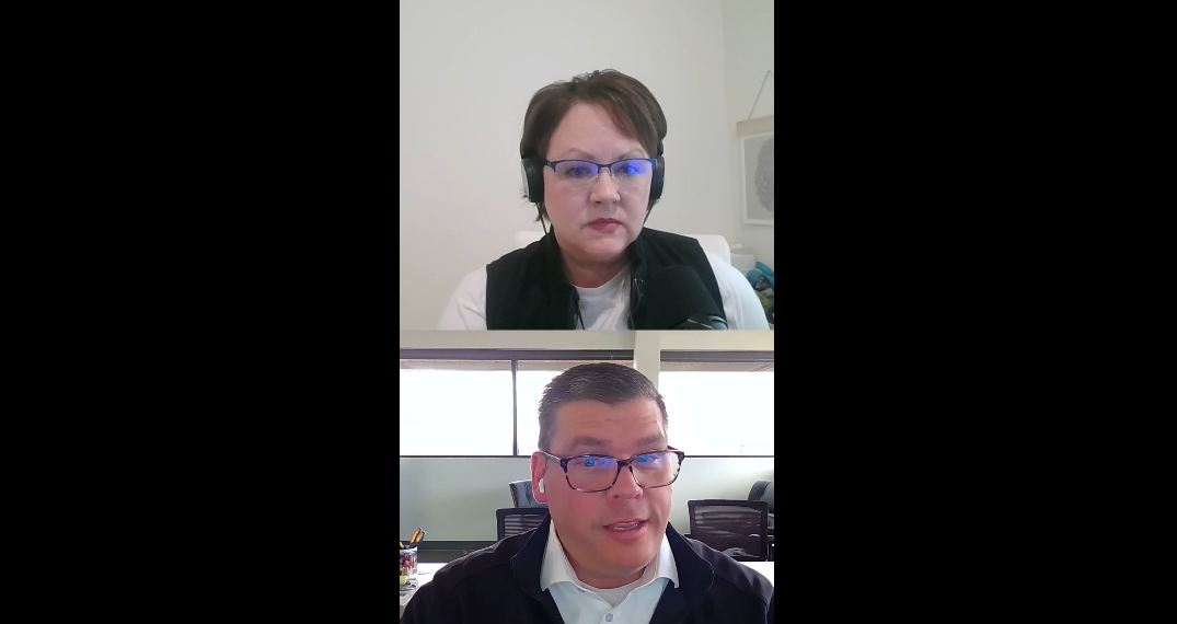 Screenshot of a video call showing two people. The person on top has short brown hair, glasses, and headphones. The person on the bottom has short dark hair, glasses, and is speaking. Both are in office settings.
