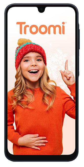 A smiling girl in an orange sweater and red knit hat stands against a light background, raising one finger as if sharing an idea. The word Troomi appears at the top of the phone screen framing her.