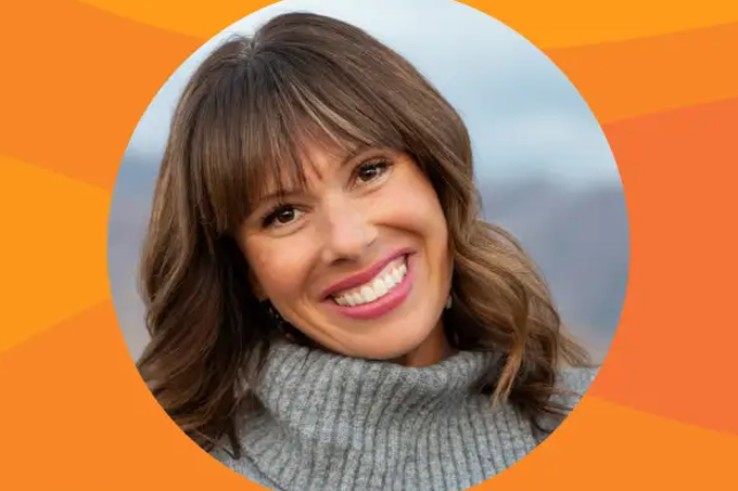 A woman with brown hair and bangs smiles, wearing a gray turtleneck sweater. The background features an orange geometric pattern and a blurred outdoor setting, evoking the welcoming atmosphere of the Troomi Parent Academy.