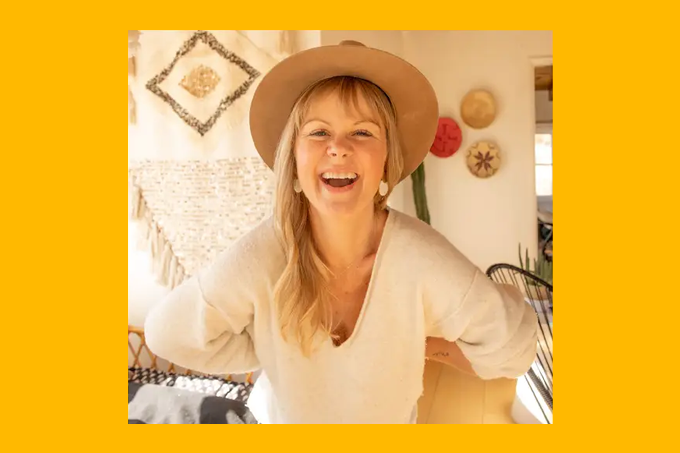 Fresh Start Family Founder Wendy Snyder is shown in a beige sweater and wide-brimmed hat leans forward indoors, with wall art and hats in the background.