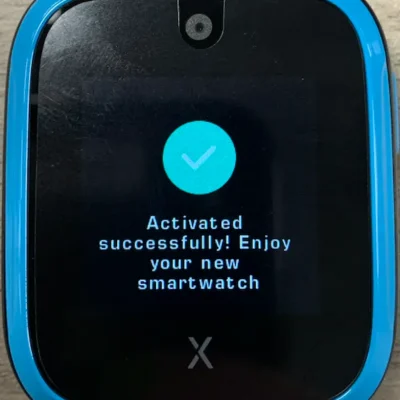 A smartwatch screen with a blue casing displays a message: Activated successfully! Enjoy your new smartwatch alongside a checkmark icon.